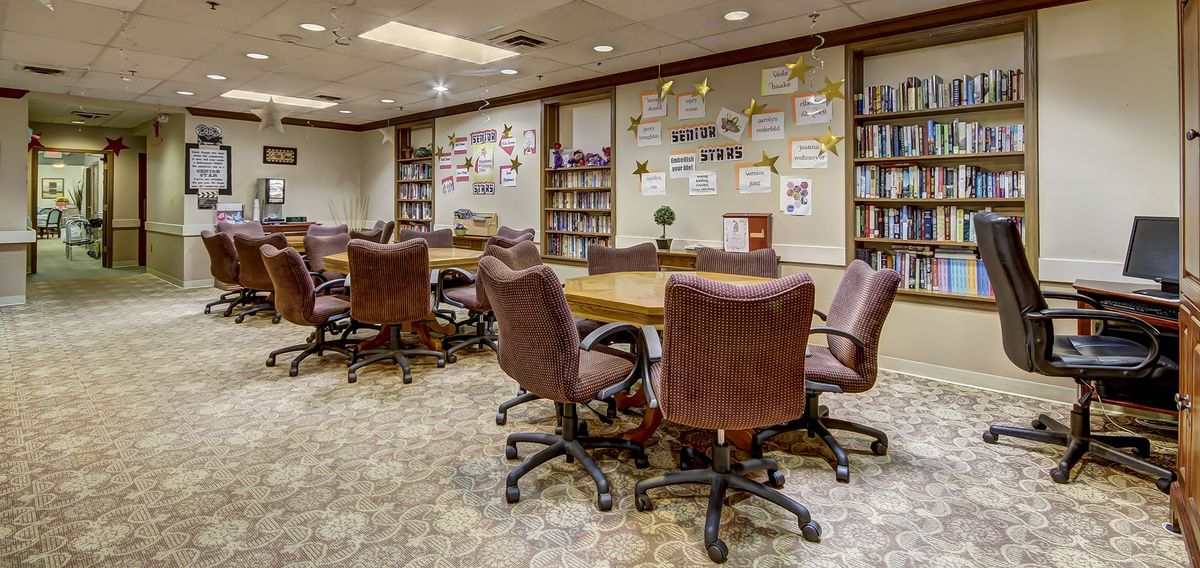 A conference room with bookshelves, tables, and chairs, resembling a library setting.