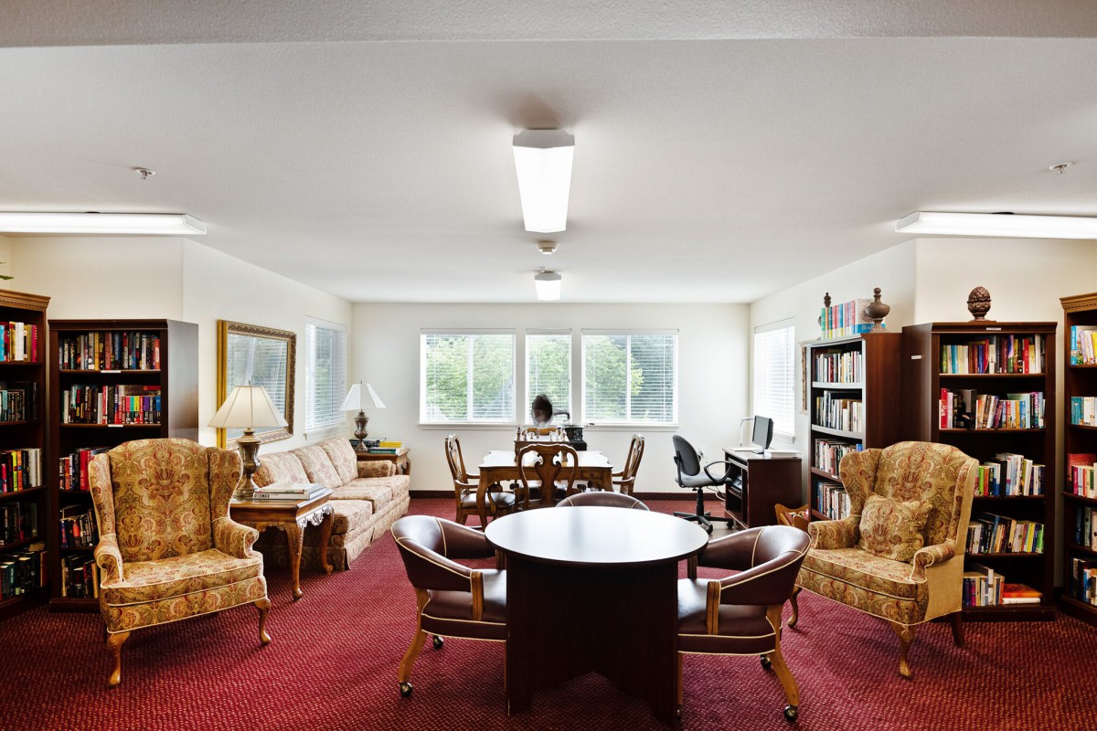 A spacious office with a round meeting table, comfortable seating, and a bookshelf along the wall.