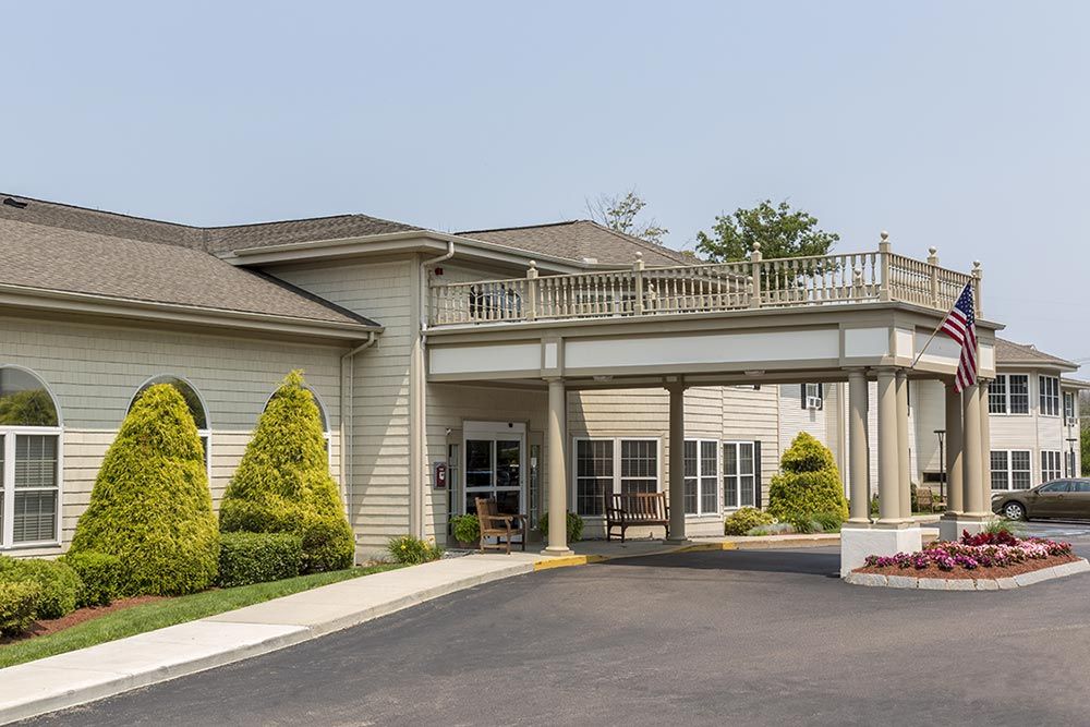 Entrance of a building with a covered driveway and landscaped surroundings.
