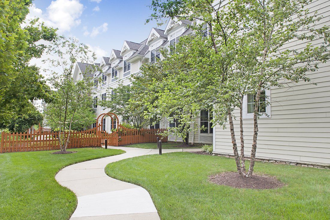 A well-maintained pathway meanders through a residential area lined with trees and greenery.
