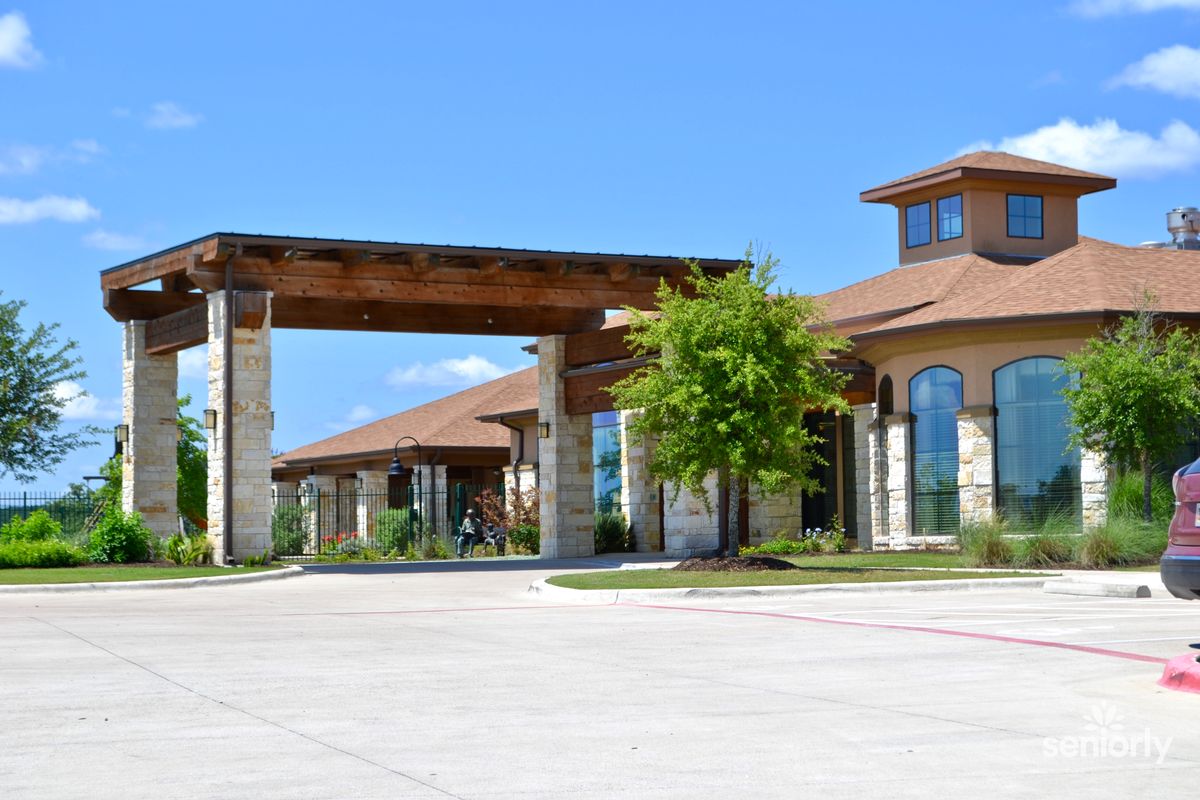 A modern building with a covered entrance and landscaped surroundings on a clear day.