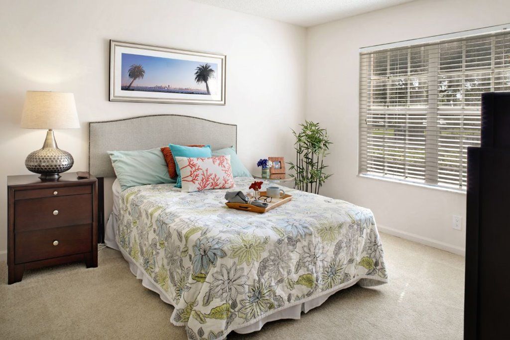 A cozy bedroom with colorful pillows, a decorative bedspread, and a window letting in natural light.