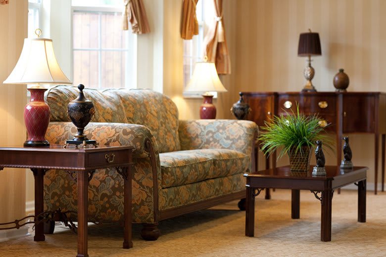 A cozy living room with a patterned sofa, wooden coffee and side tables, and decorative lamps.