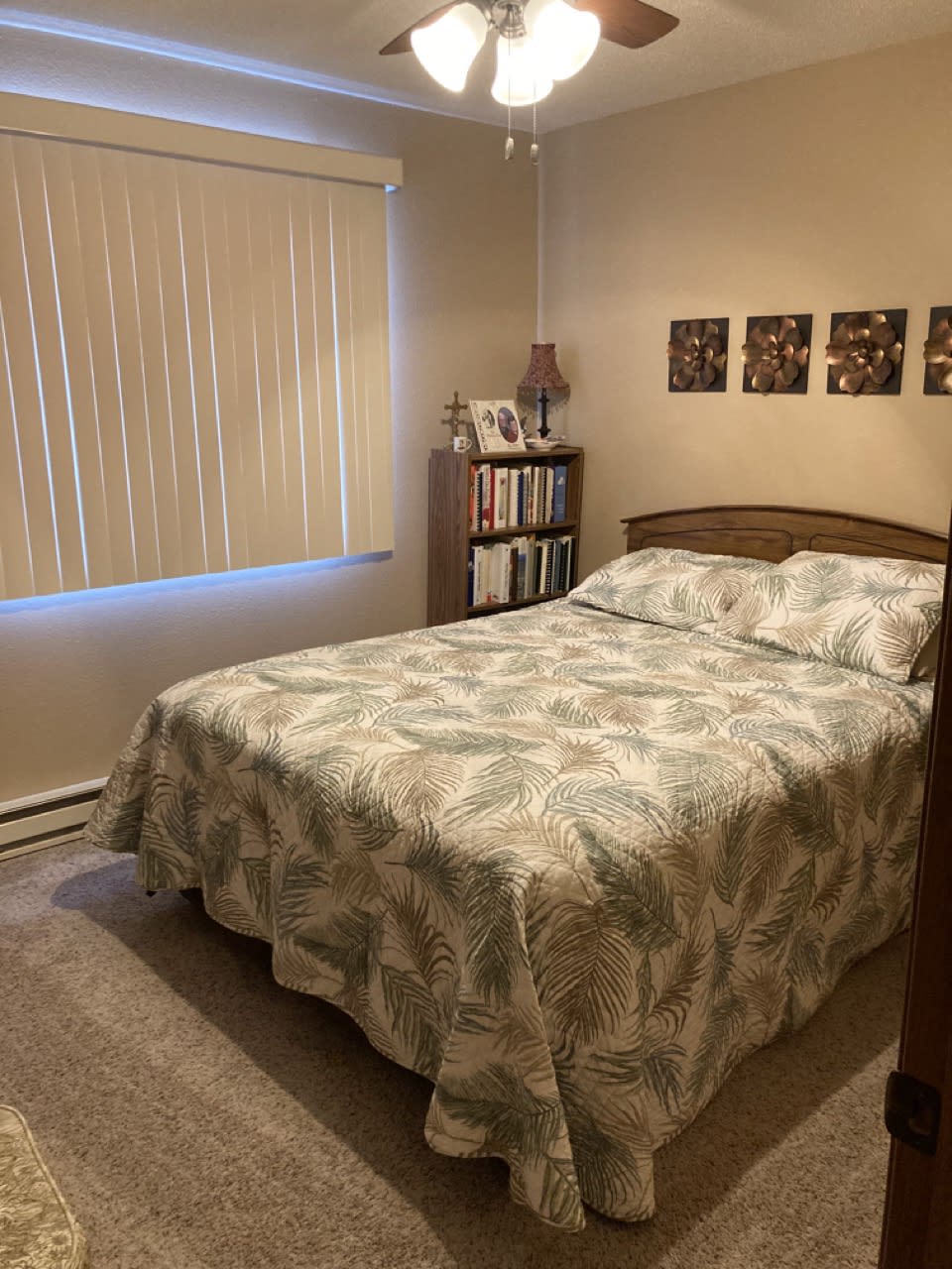 Cozy bedroom with a neatly made bed and a small bookshelf.