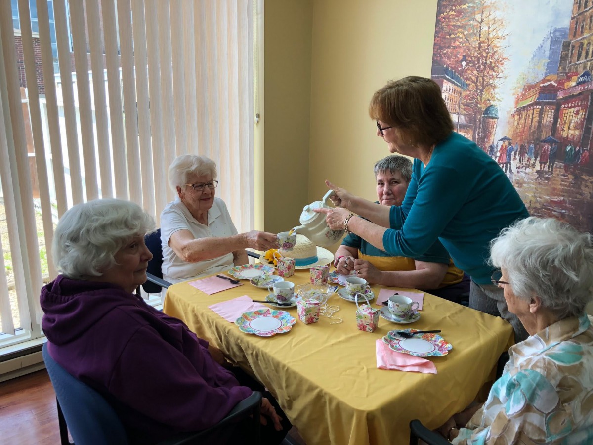 A group of elderly women enjoying a tea party together at a table.