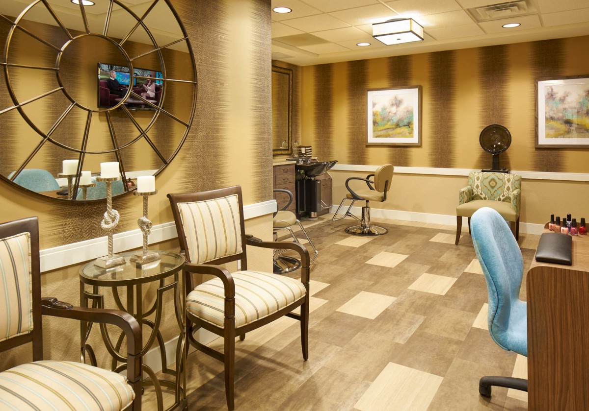 A well-decorated salon featuring stylish chairs, a large mirror, and elegant lighting.