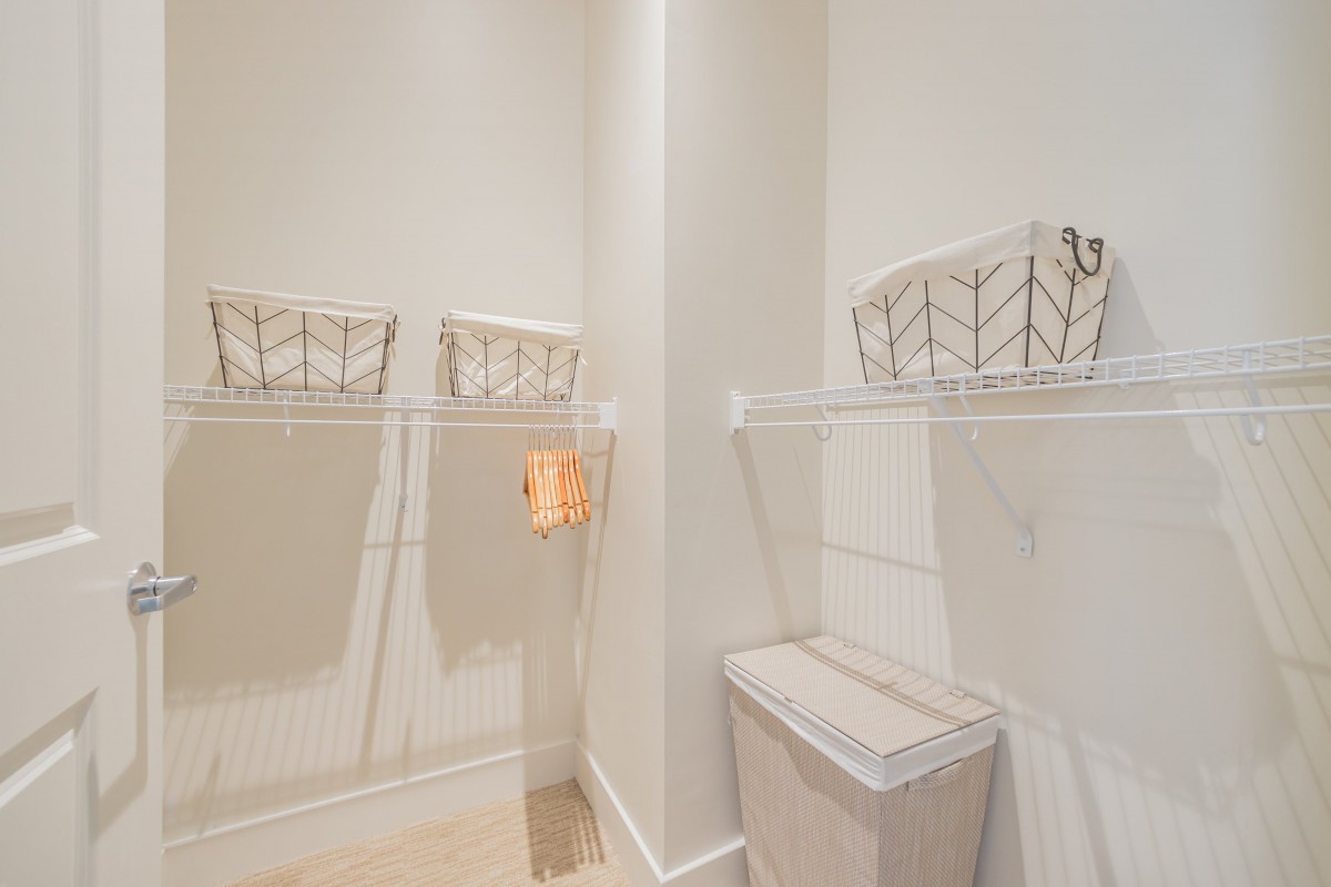 A modern and minimalist laundry room with shelves and storage baskets.
