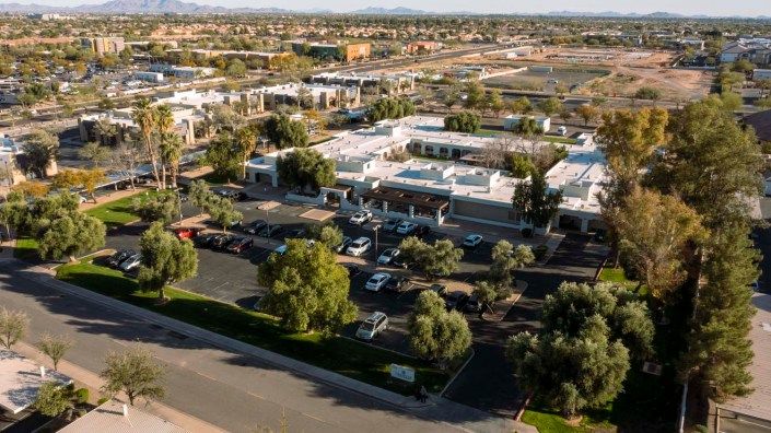 Aerial view of a commercial area with buildings and parking lots surrounded by trees.