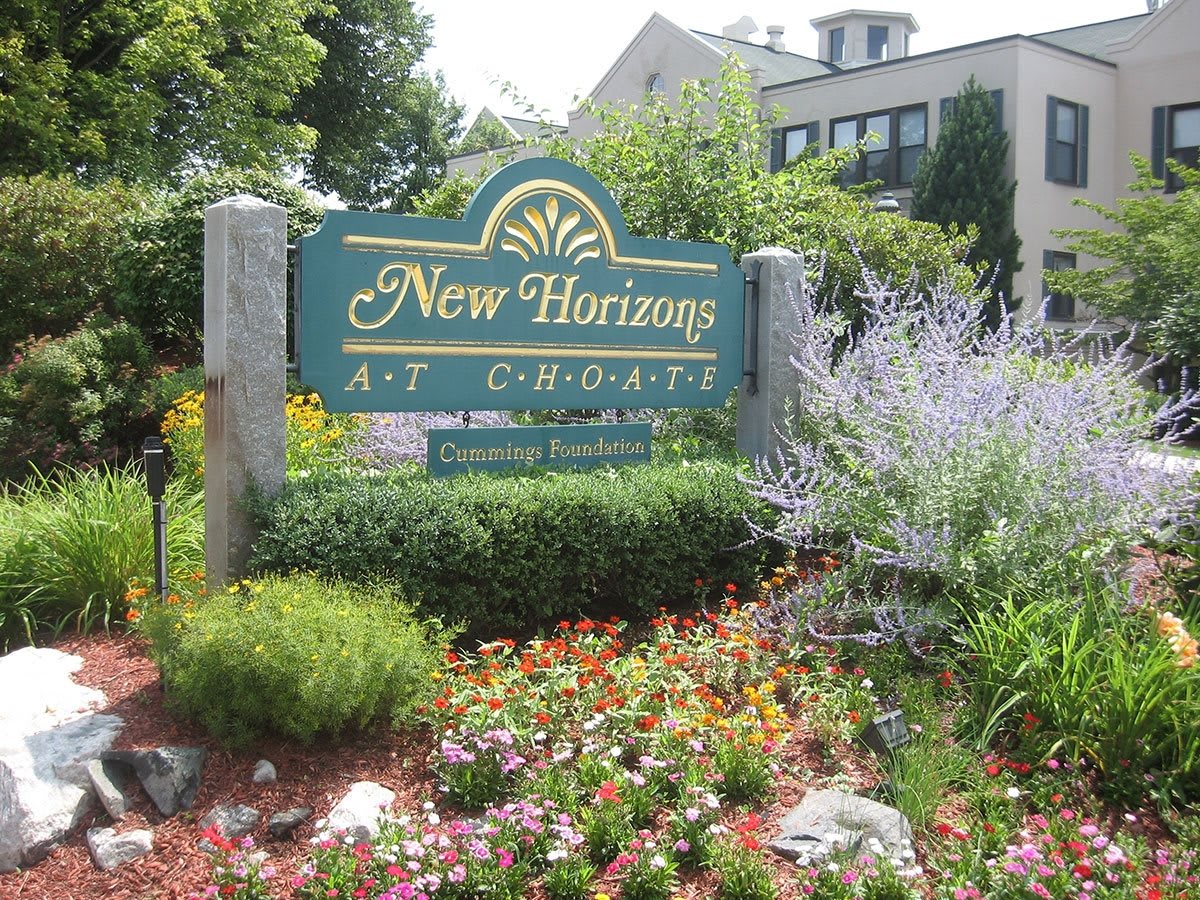 A sign for 'New Horizons' surrounded by a colorful garden and plants.