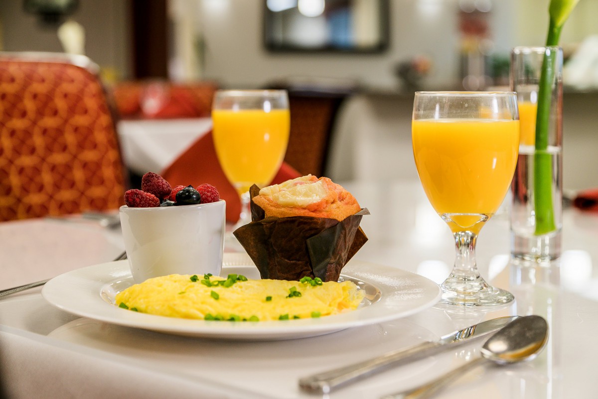 A delicious breakfast spread featuring an omelette, a muffin, a bowl of berries, and glasses of orange juice.