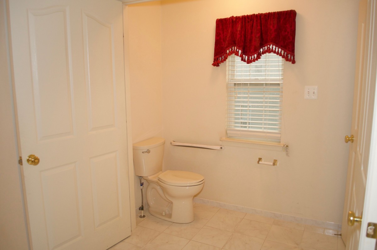 A simple bathroom with a toilet and a window featuring a red curtain.