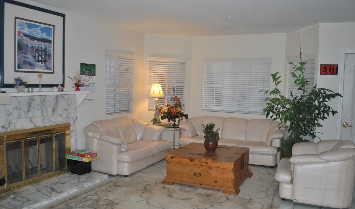 A cozy living room with white sofas, a wooden coffee table, and indoor plants.