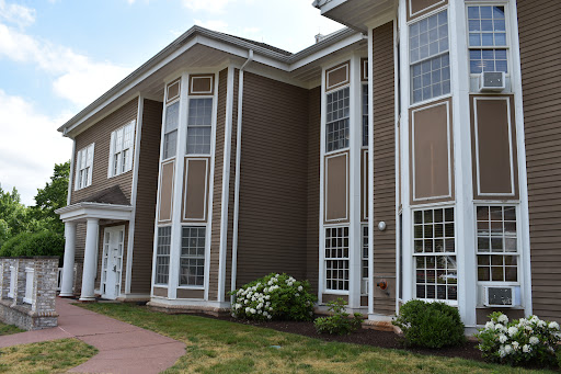 A modern residential building featuring large windows and a well-maintained lawn.