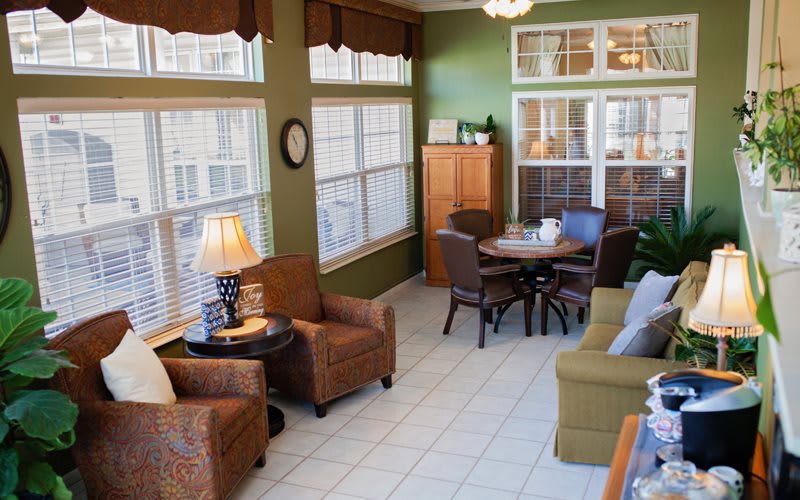 A cozy living room with abundant natural light, featuring comfortable seating and warm decor.