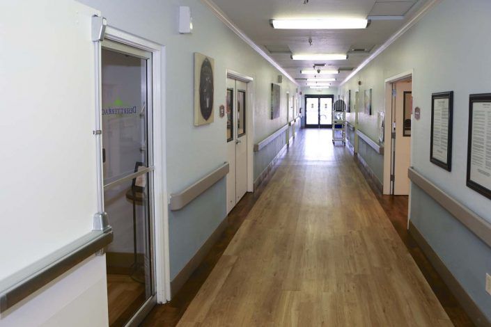 A quiet hospital corridor with doors on either side leading to patient rooms.