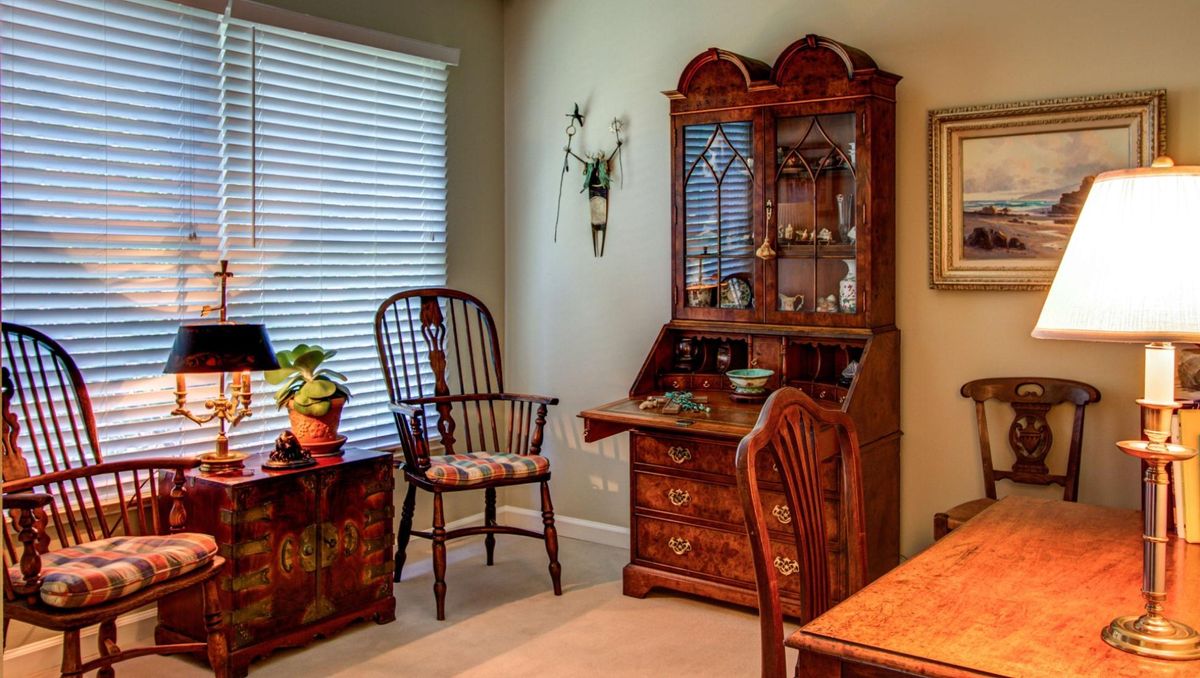 A cozy living room corner featuring an antique wooden desk and chair.