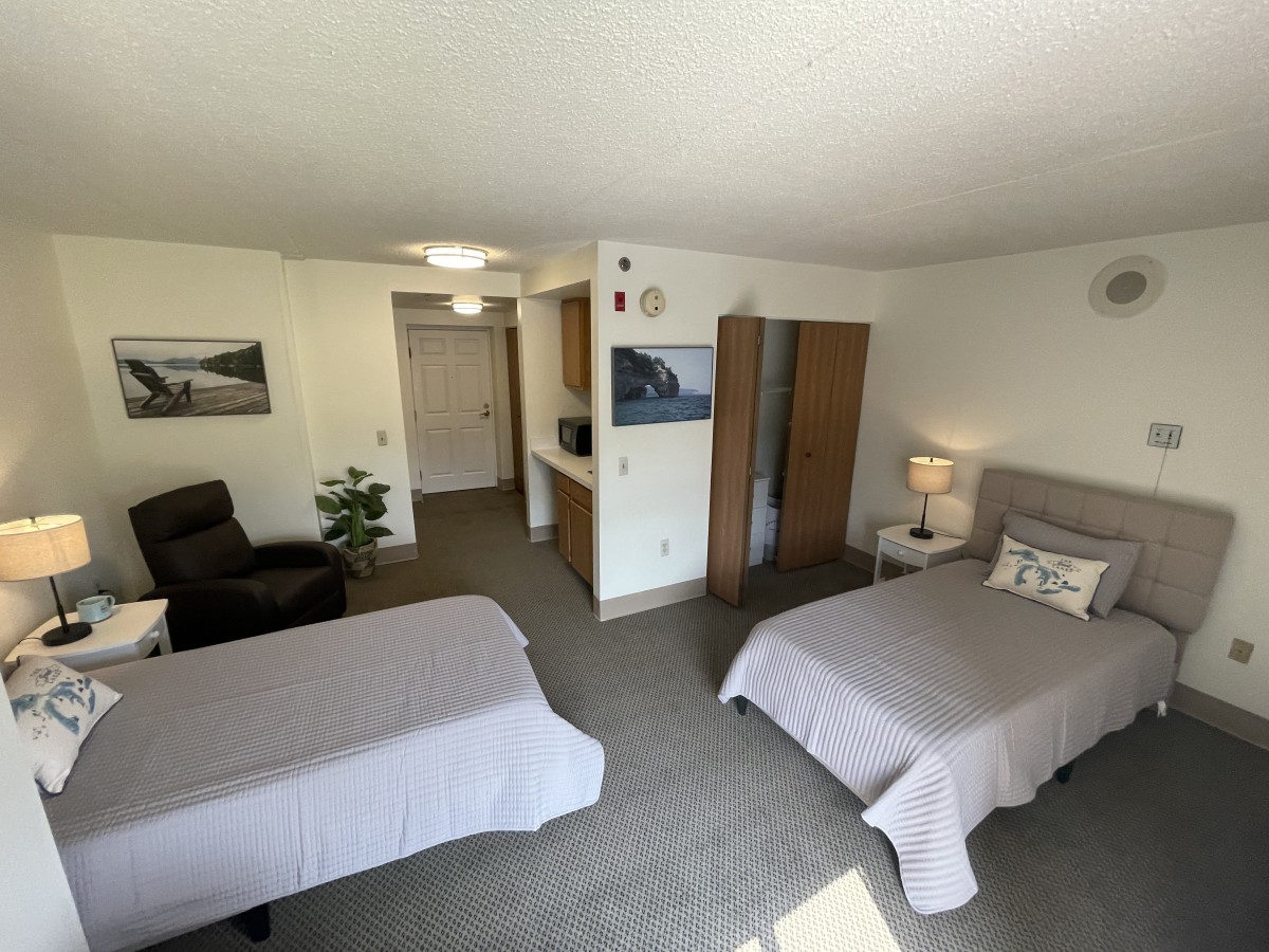 A cozy bedroom with twin beds, a wardrobe, and a seating area.