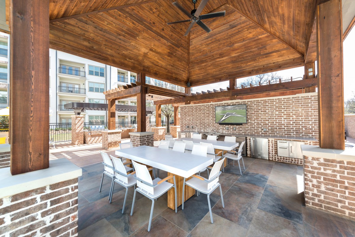 A modern outdoor patio with a dining area under a wooden pergola.