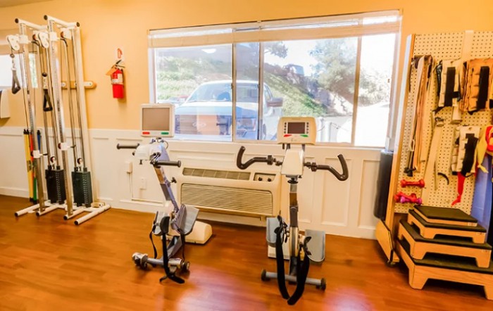 A bright workout room featuring two exercise bikes in front of a large window.