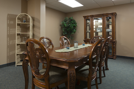 A cozy dining room featuring a wooden table surrounded by elegant chairs, complemented by a glass cabinet and indoor greenery.
