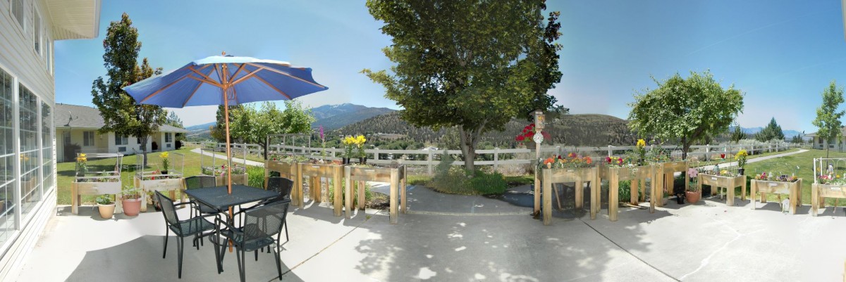 A scenic outdoor patio area with seating, umbrellas, and a view of the mountains in the background.