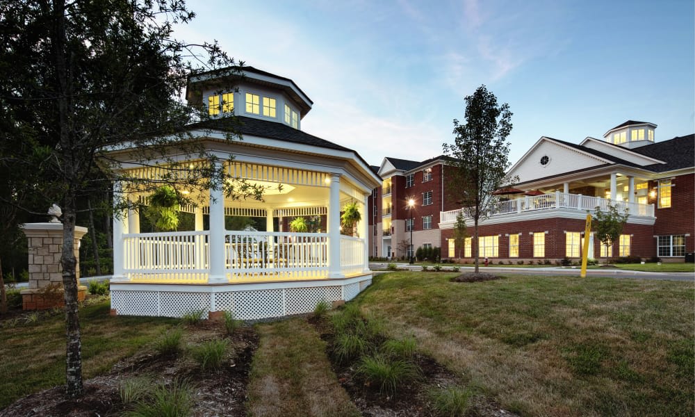 A gazebo illuminated in the evening light with a building in the background.