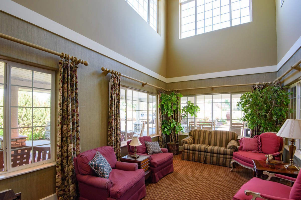 A spacious living room with high ceilings, large windows, and comfortable seating.