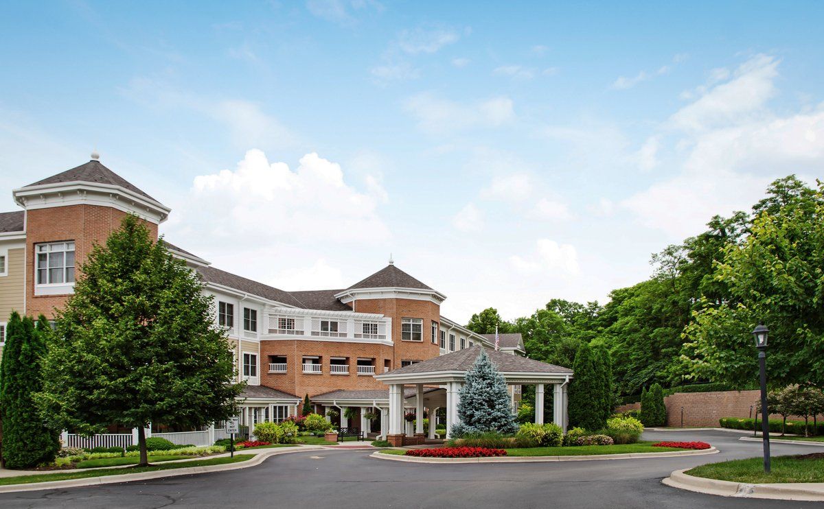 A picturesque residential building surrounded by lush greenery and a clear blue sky.