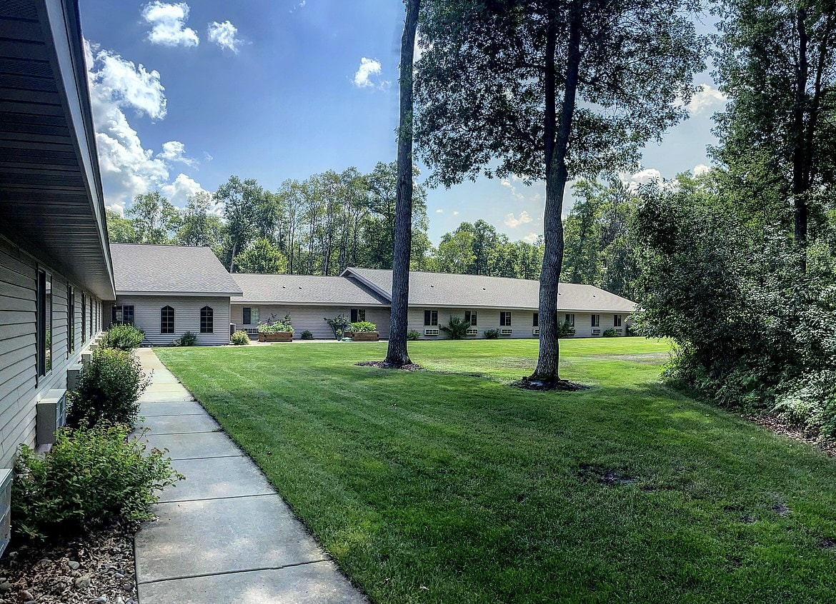 A suburban house with a well-maintained lawn and trees on a sunny day.