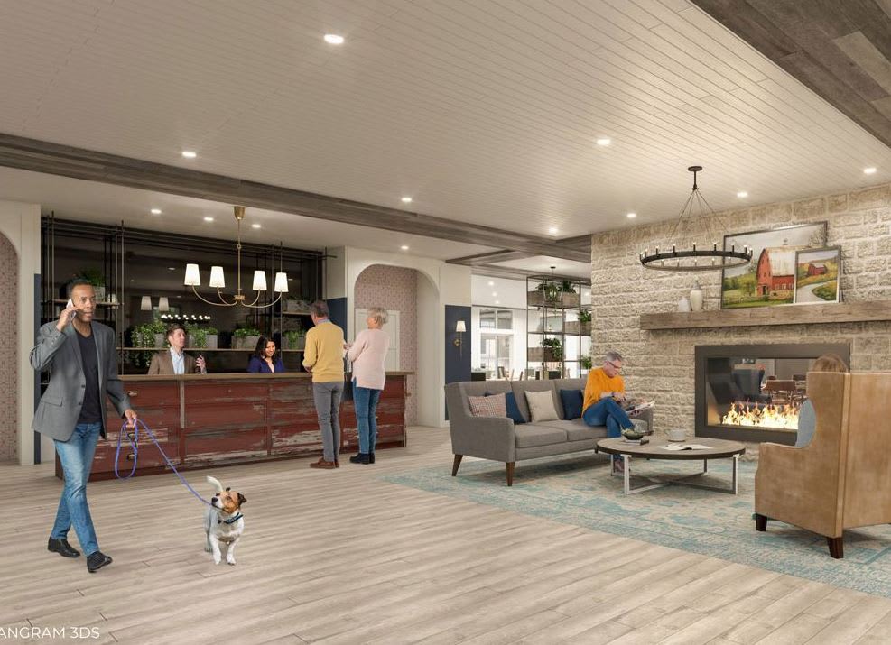 A modern lobby with a bar, fireplace, and seating area bustling with people and a dog.