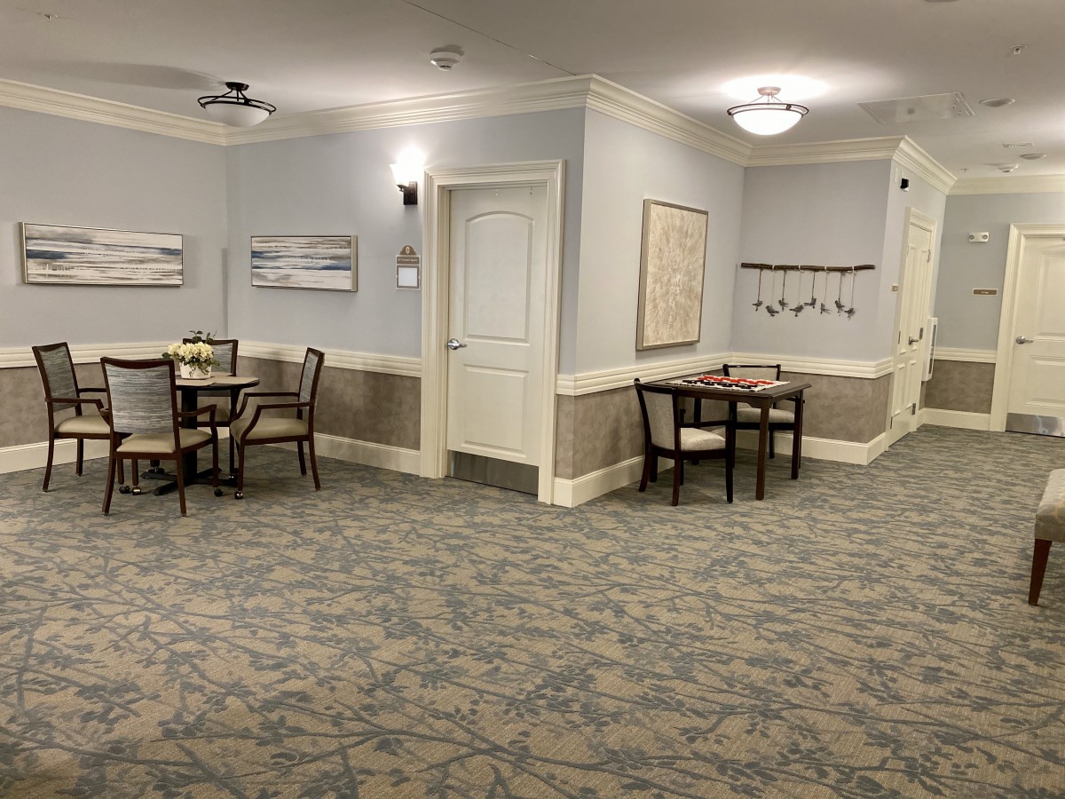 A quiet waiting area with tables and chairs, featuring soft lighting and wall art.