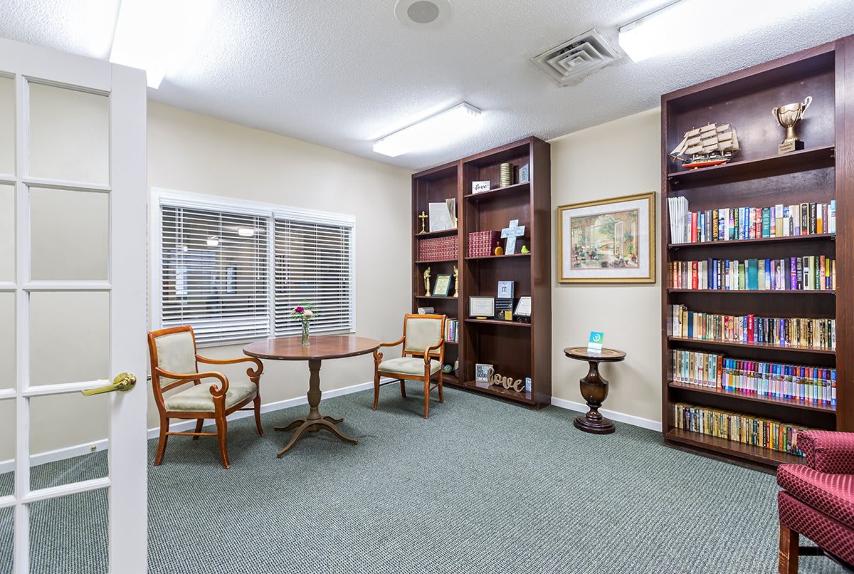 A cozy library interior with shelves full of books, a small round table, and two chairs.