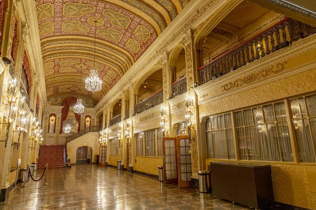 A grand theater lobby with an ornate ceiling and elegant chandeliers.