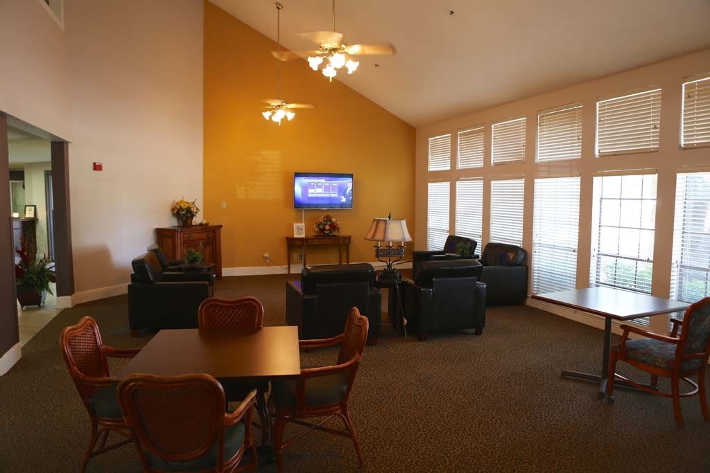 A cozy living room featuring comfortable seating, a television, and large windows.