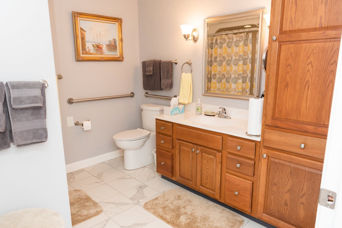 A well-lit bathroom with wooden cabinetry and tiled flooring.