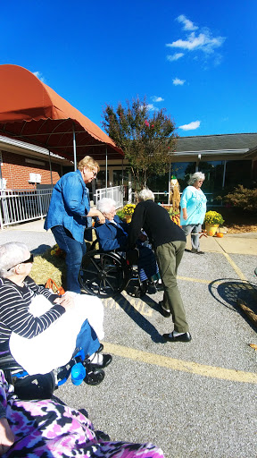Caregivers assisting elderly individuals during a community event in a sunny outdoor setting.
