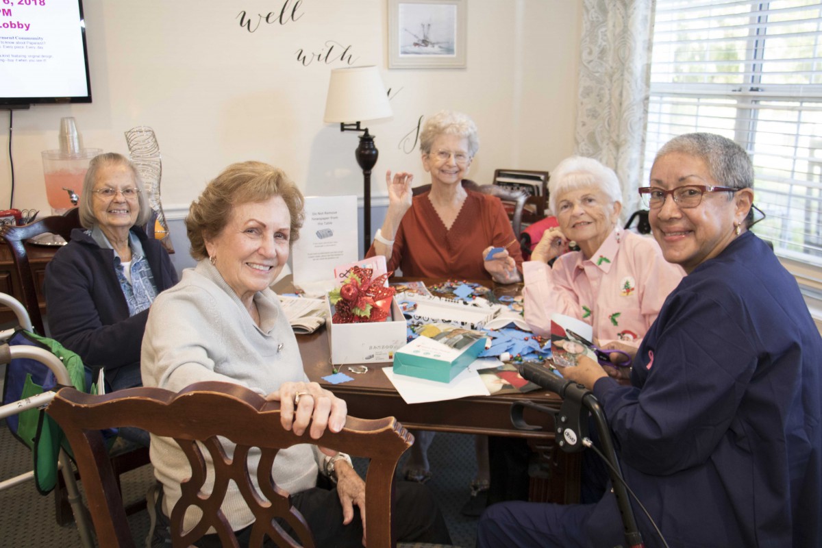 A group of seniors enjoying a casual gathering indoors, smiling and engaging in a shared activity.