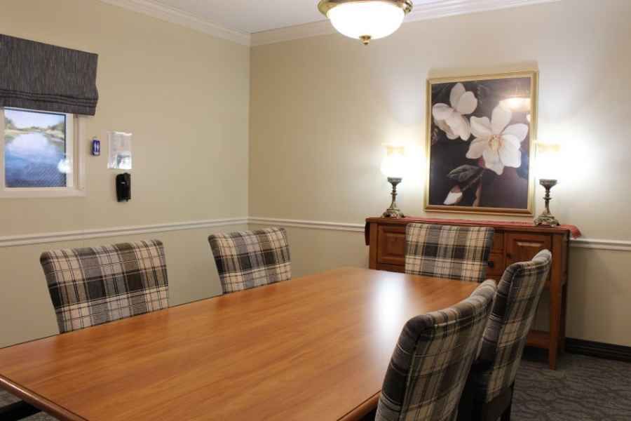 A cozy dining room with a wooden table, plaid chairs, and flower-themed artwork on the wall.