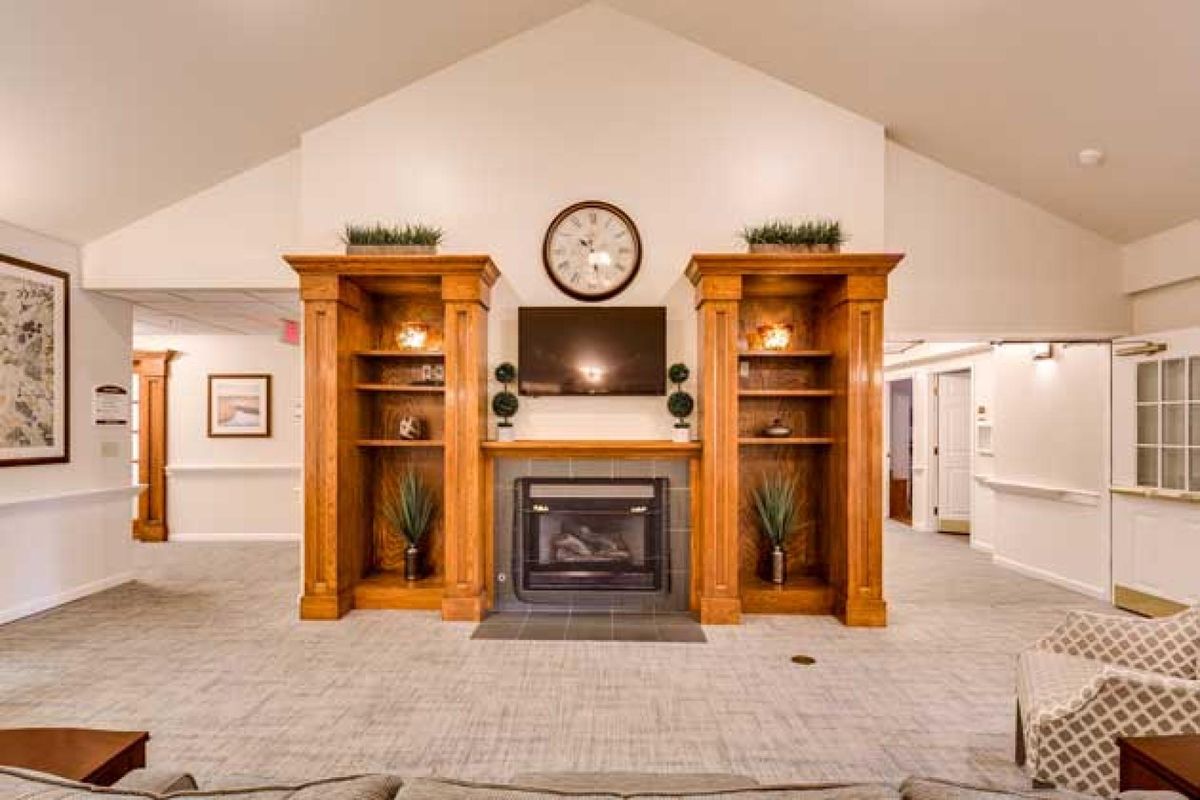 A cozy living room with a fireplace, flanked by wooden bookshelves and a television mounted above it.