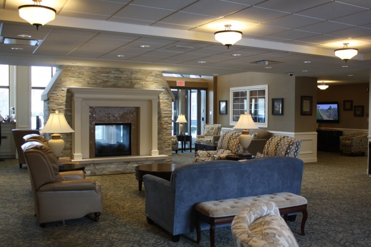 A cozy lobby area featuring a fireplace surrounded by comfortable sofas and ambient lighting.