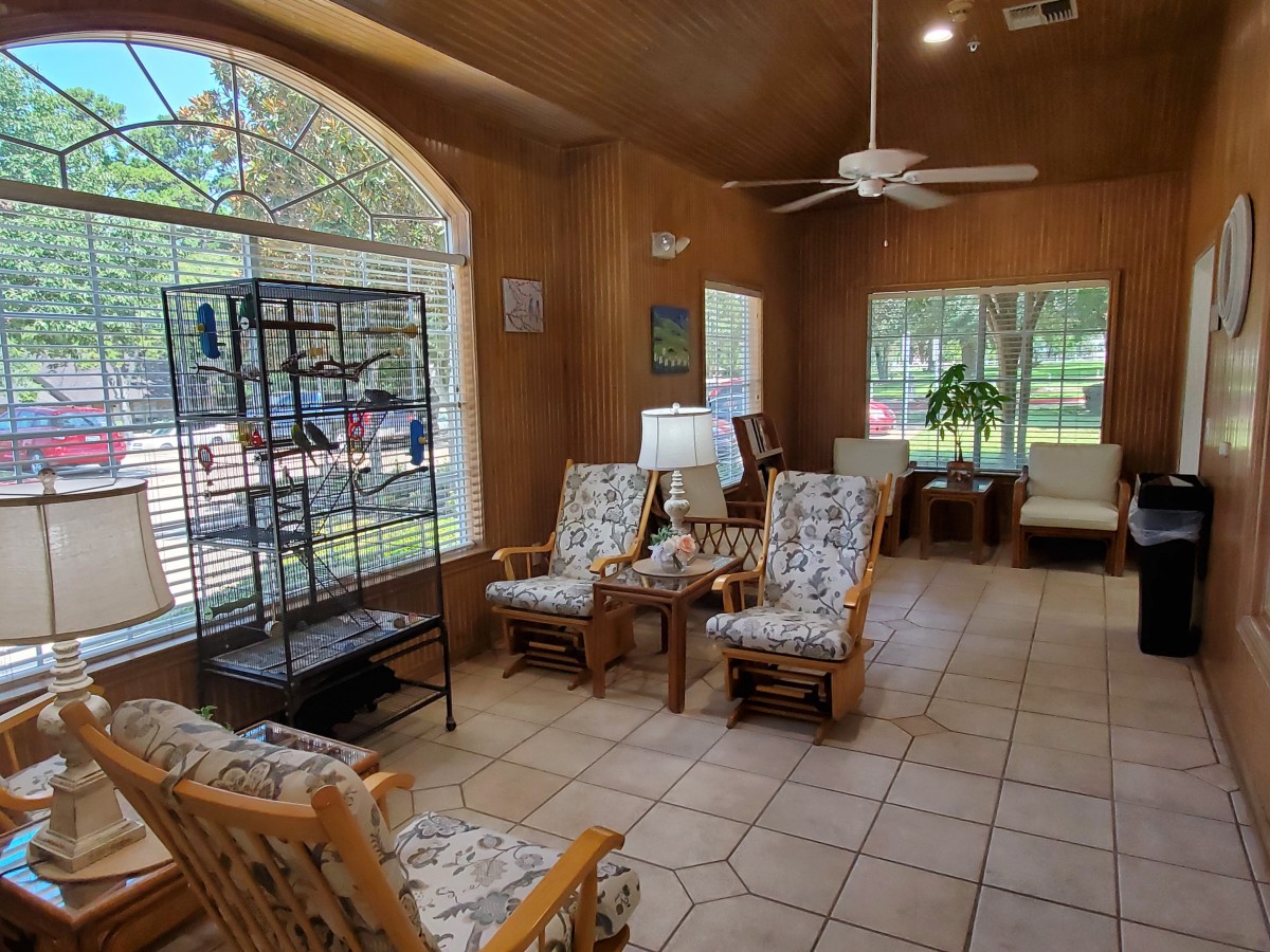 A cozy living room with wicker furniture, large windows, and abundant natural light.