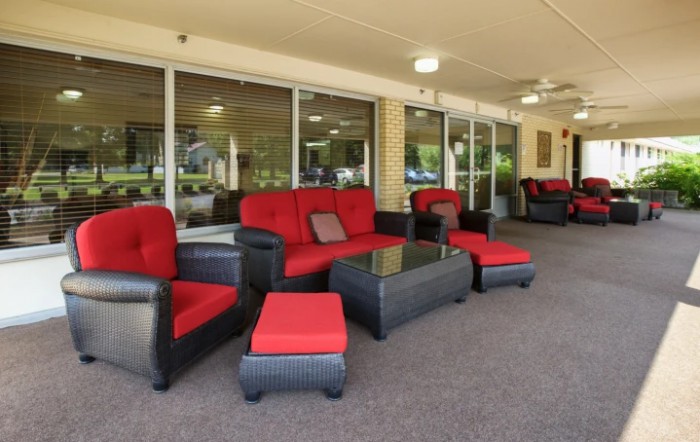 A stylish outdoor seating area featuring red-cushioned wicker furniture under a covered patio.