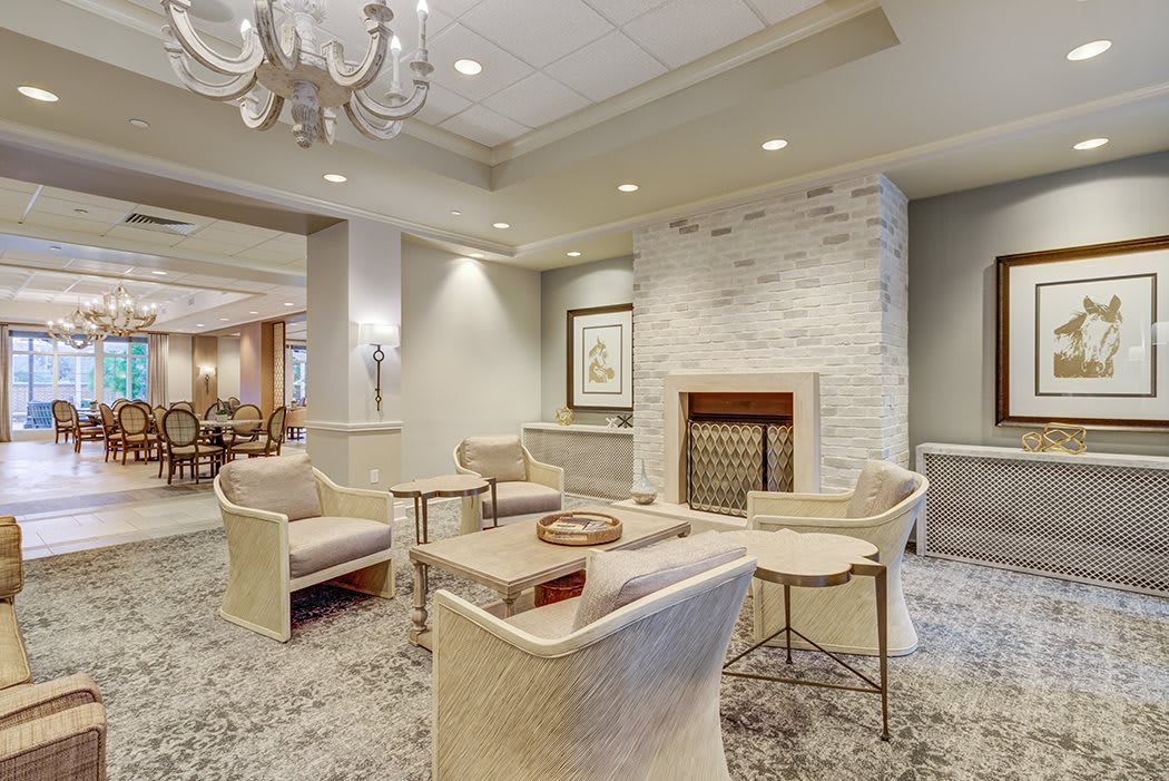 A modern living room with a cozy seating area, featuring a fireplace and elegant chandelier.