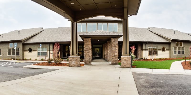 A modern building with a brick facade and a covered entrance supported by columns.