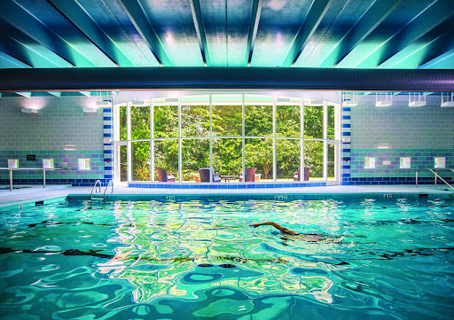 A serene indoor swimming pool with a beautiful view of nature through large windows.