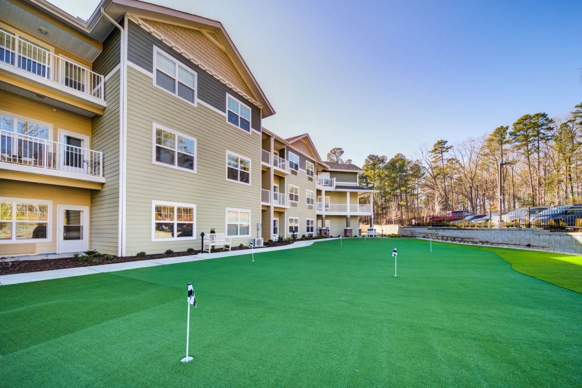 A modern apartment building with a golf putting green in the foreground.