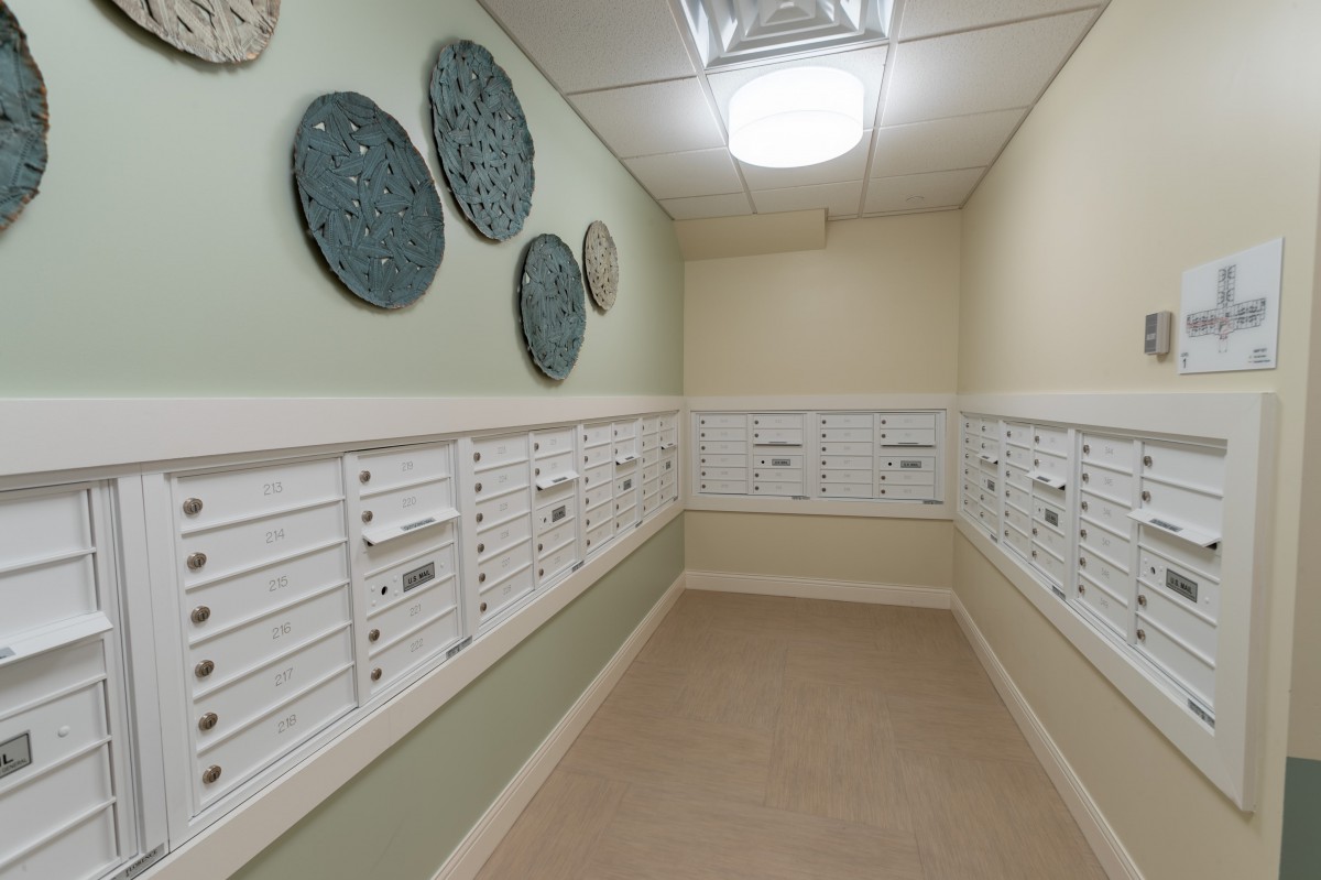 A mailroom with multiple white mailboxes and decorative wall art.