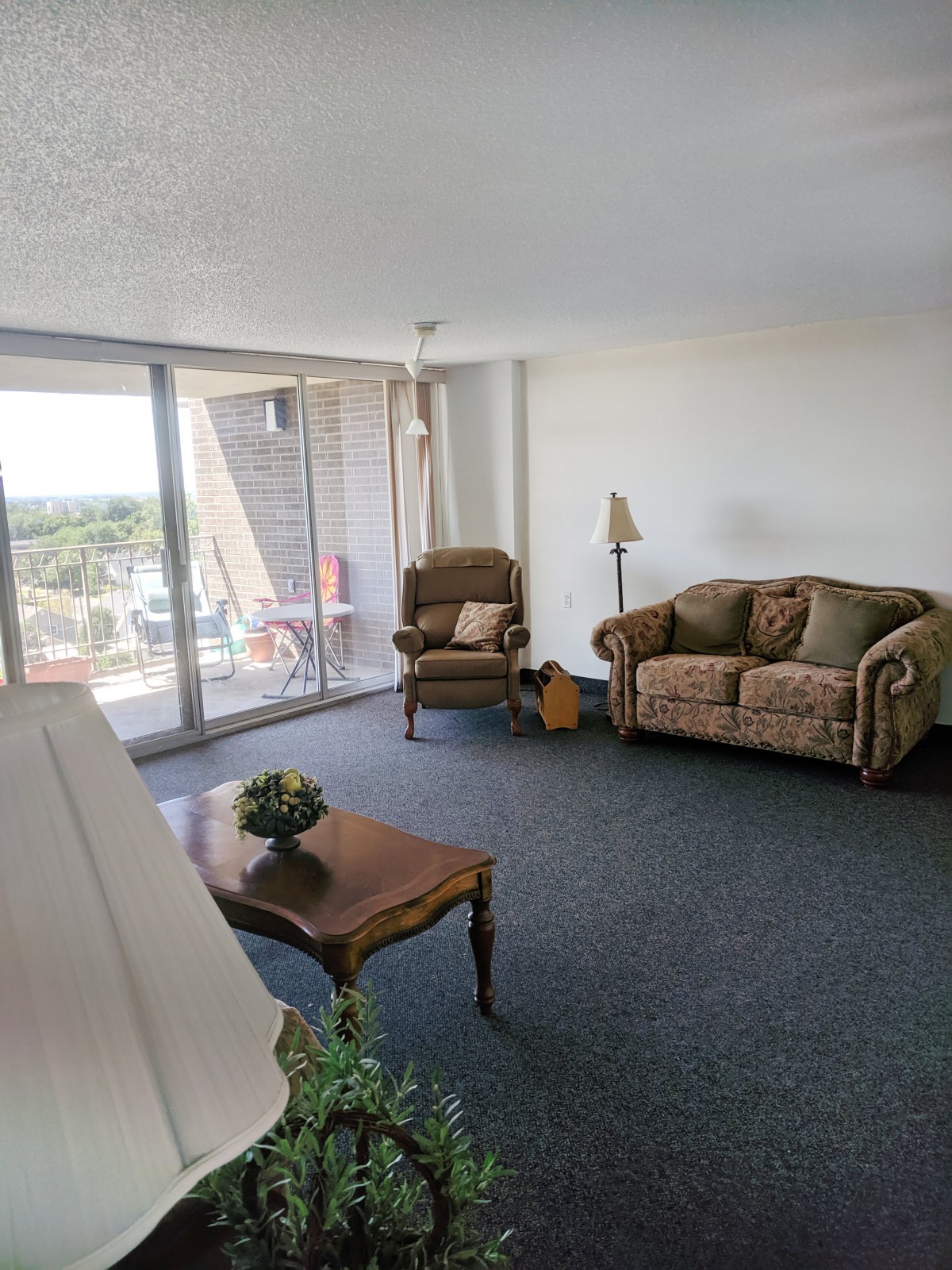 A cozy living room with a sofa, armchair, and coffee table facing large windows that let in natural light.