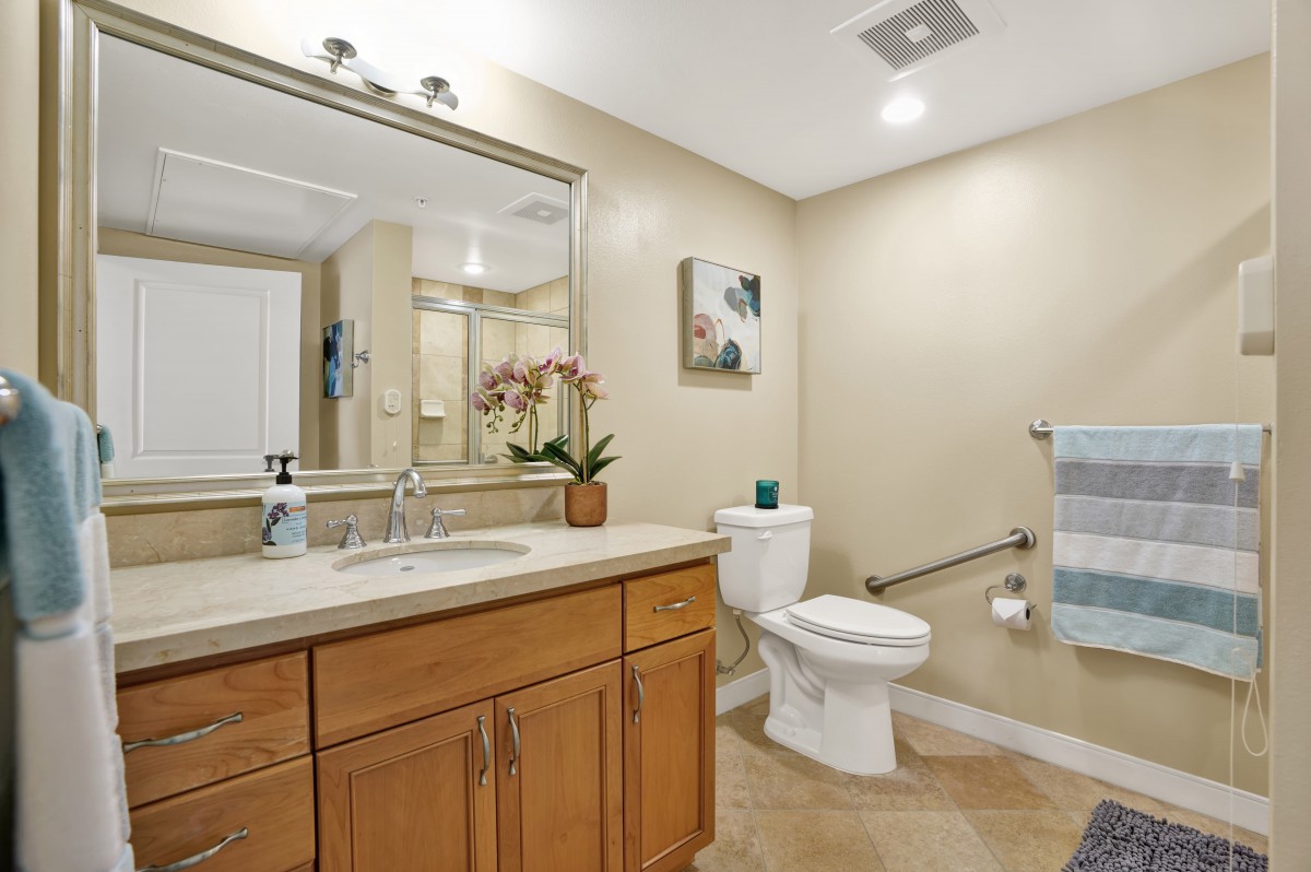 A modern bathroom with a large mirror, wooden cabinets, and decorative accents.