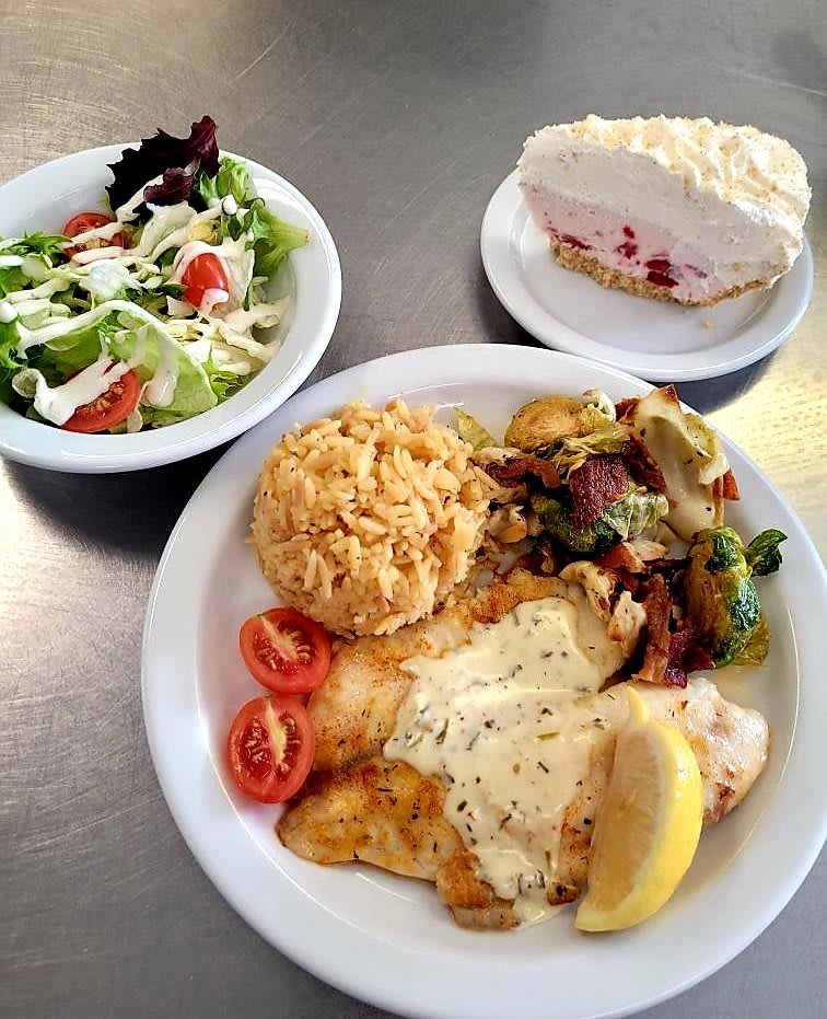 A plated meal featuring fried chicken, roasted potatoes, a fresh salad, and a slice of pie for dessert.